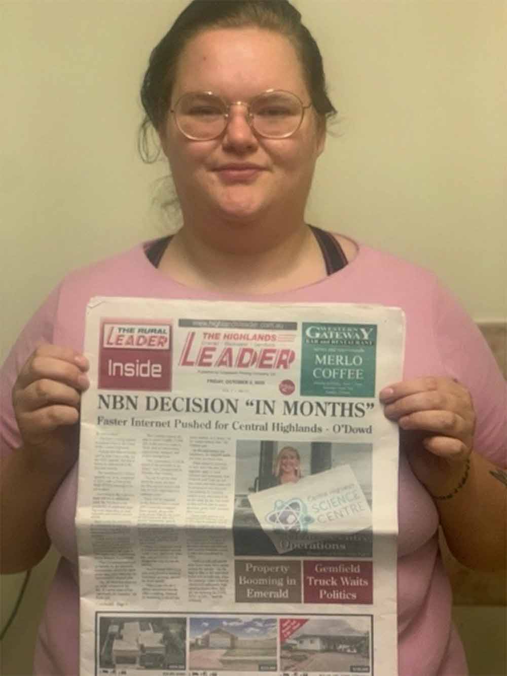 Ali holds up the front page featuring a newspaper article she has co-written