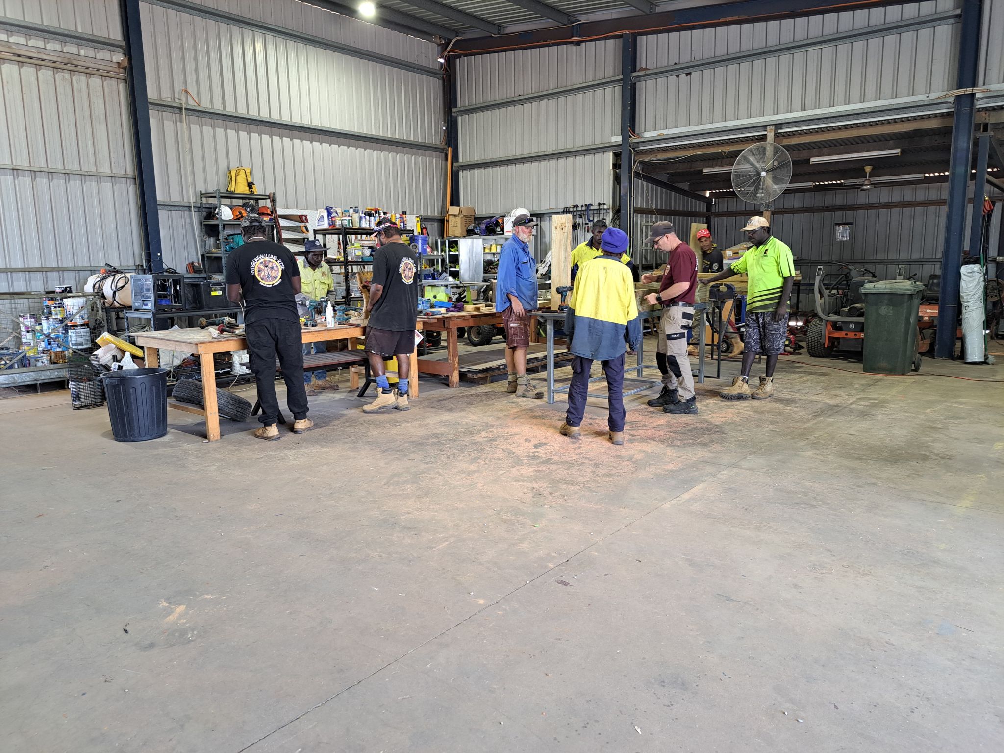 A group of First Nations men in a tin shed working on different pieces of word to hone their carpentry skills