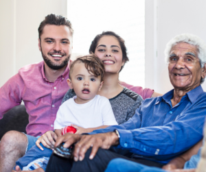 Three generations of a family sit together smiling at the camera